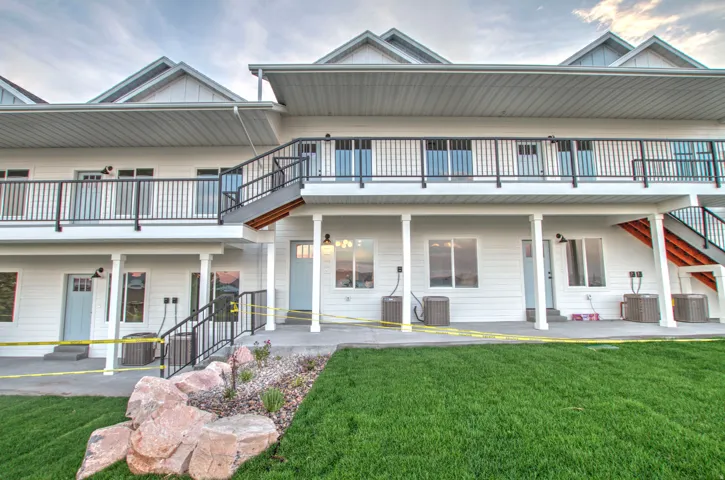 Multi-level structure featuring white siding, black railings, and multiple entryways