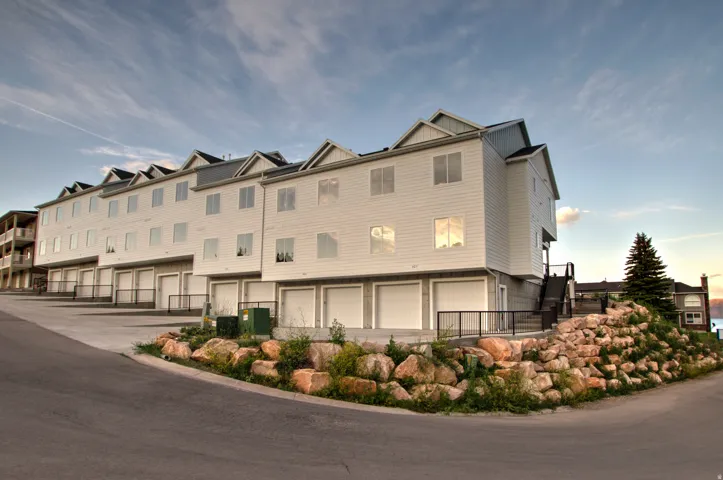 Multi-story residential building featuring white siding and multiple attached garages