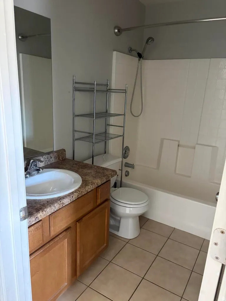 Bathroom featuring a vanity with wood-finish cabinetry, solid surface countertop, and integrated sink