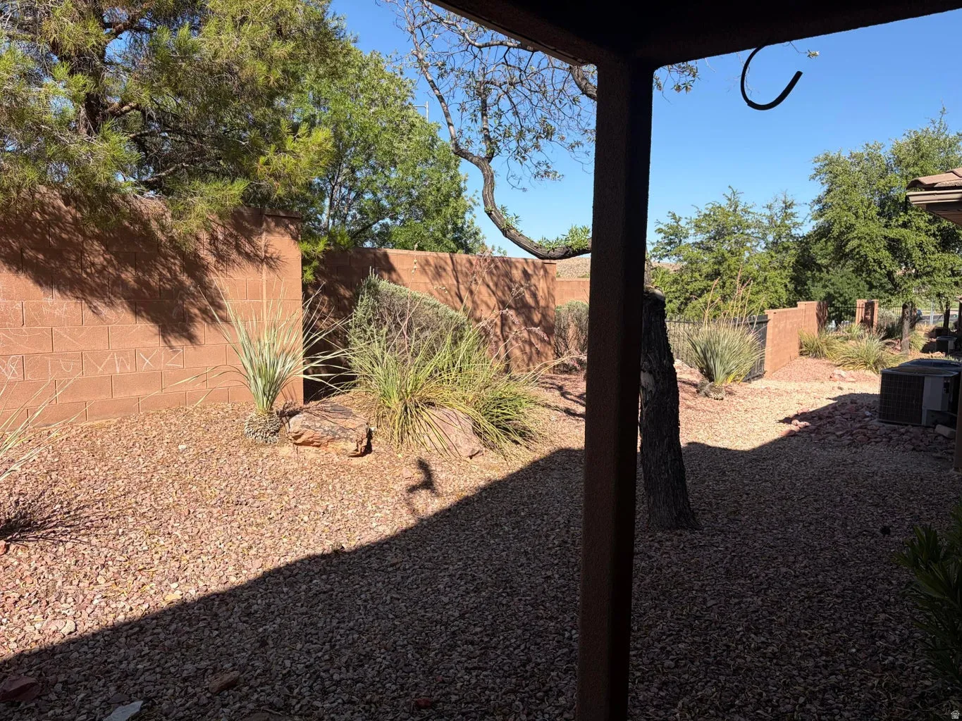 Landscaped backyard featuring gravel ground cover, mature trees, and privacy walls