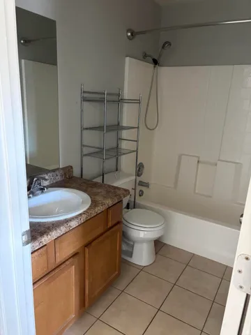 Bathroom featuring a vanity with wood-finish cabinetry, solid surface countertop, and integrated sink