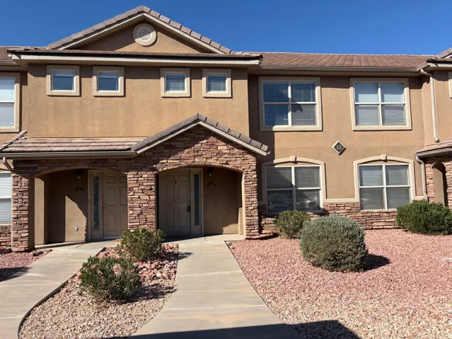 Stucco exterior featuring stacked stone accents and a terracotta-style tile roof