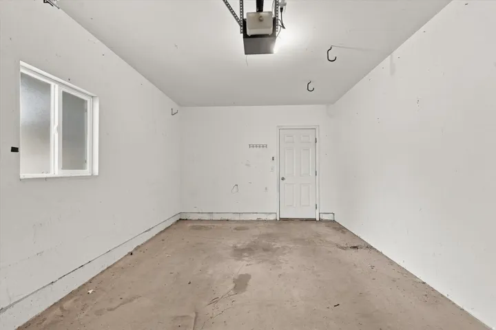 Garage space with a window, painted walls, and a service door