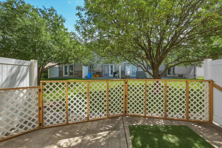 Patio area featuring concrete flooring, a lattice-style fence with a gate, and a section of artificial turf