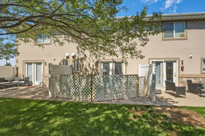 Rear exterior featuring two private patio areas, stucco facade, stone accents, multiple sliding glass doors, and upper-level windows