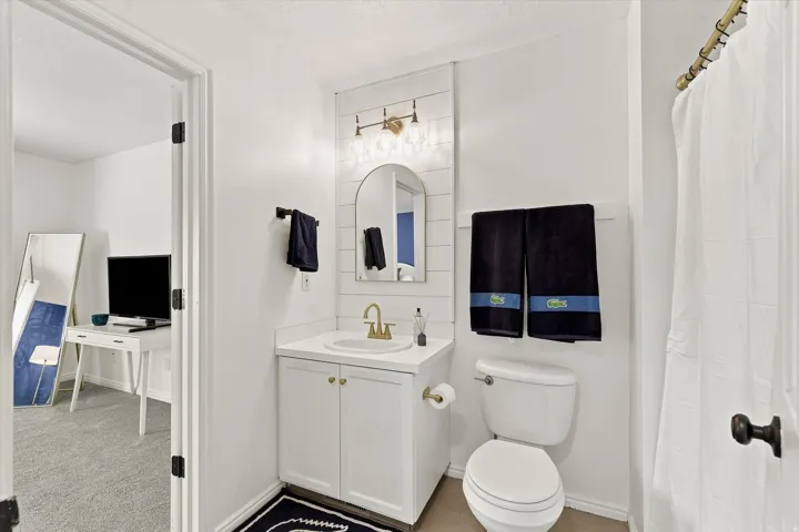 Bathroom featuring a white vanity with gold-finish hardware, a white sink basin, and a gold-finish faucet