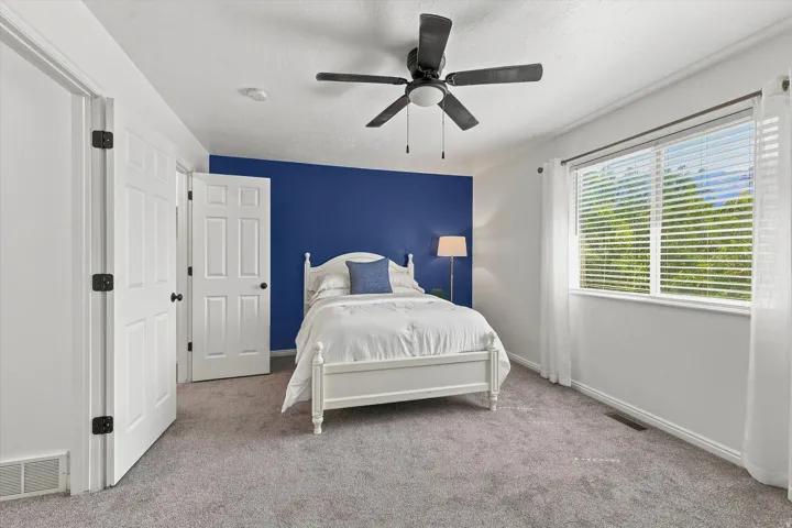 Interior room featuring a large window with white blinds, a ceiling fan with light fixture, and two white paneled doors