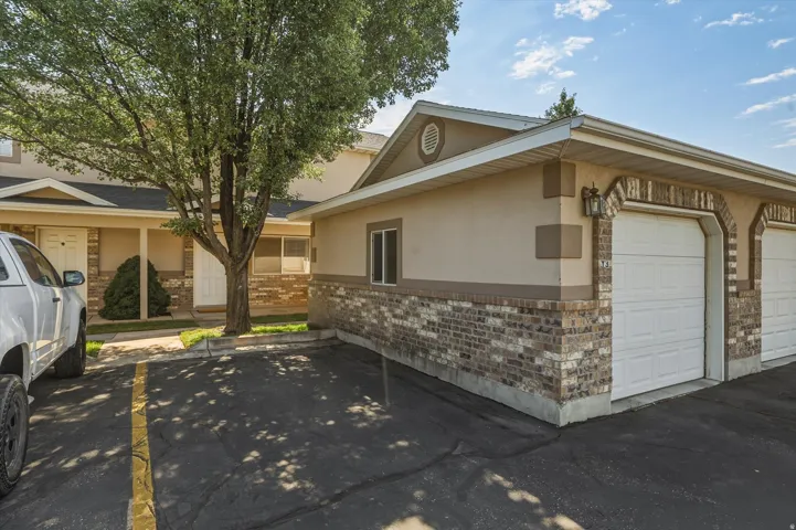Exterior featuring a brick and stucco facade, attached garage with arched brick detailing, and a front entry porch