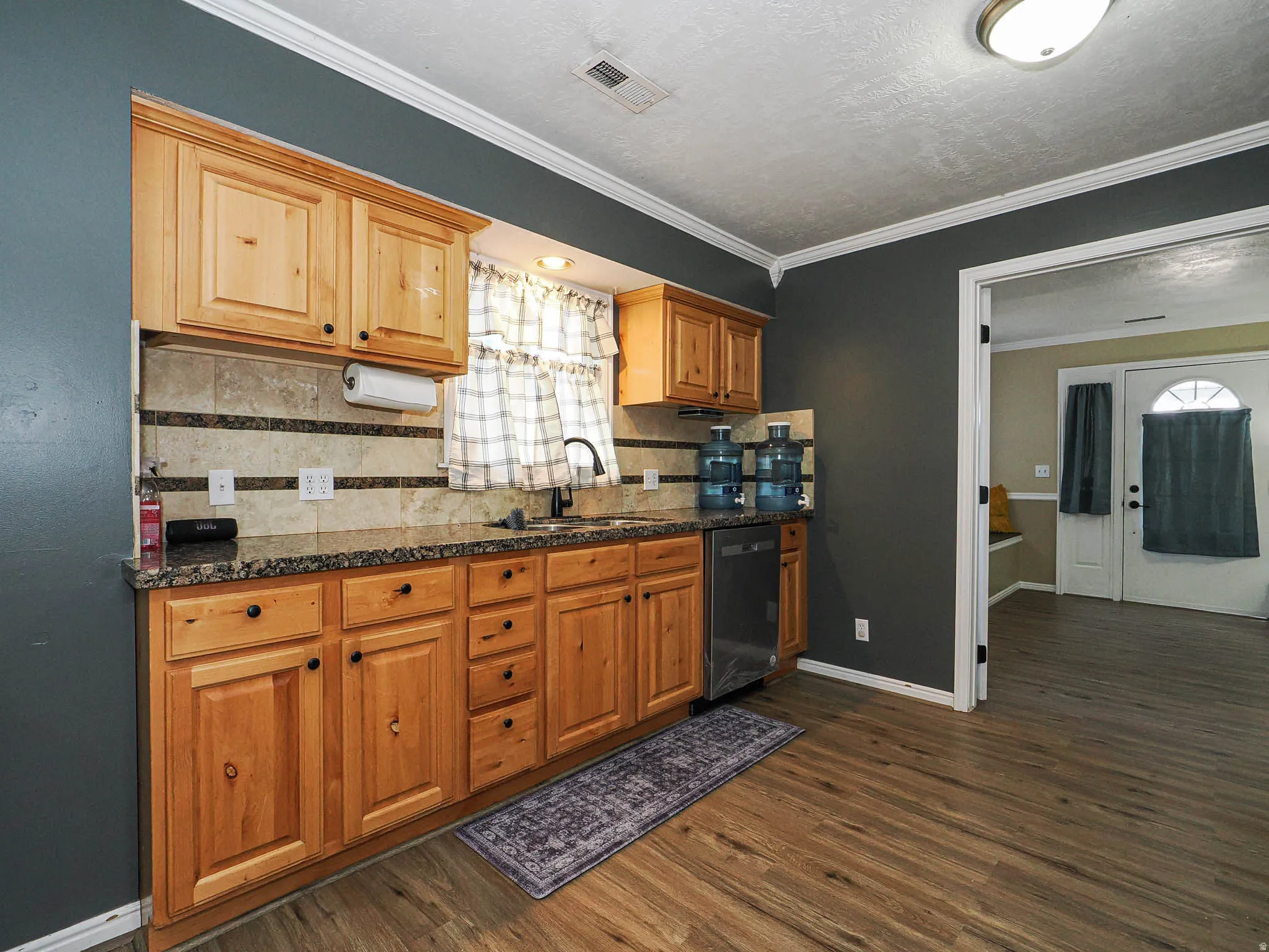 Kitchen featuring wood cabinetry, granite-style countertops, a tiled backsplash, and wood-finish flooring