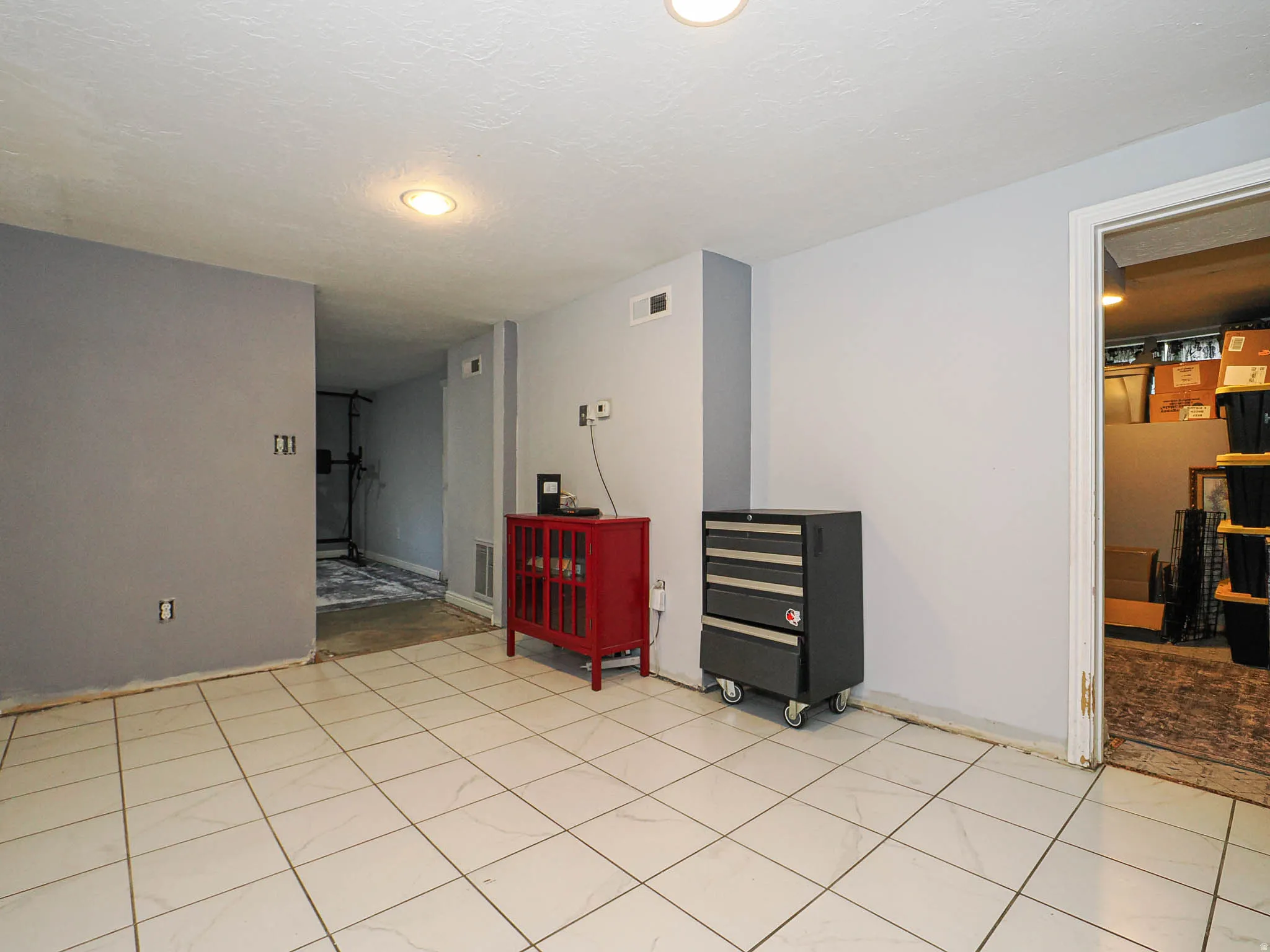 Spacious room featuring light-colored tile flooring, recessed lighting, and a neutral wall palette