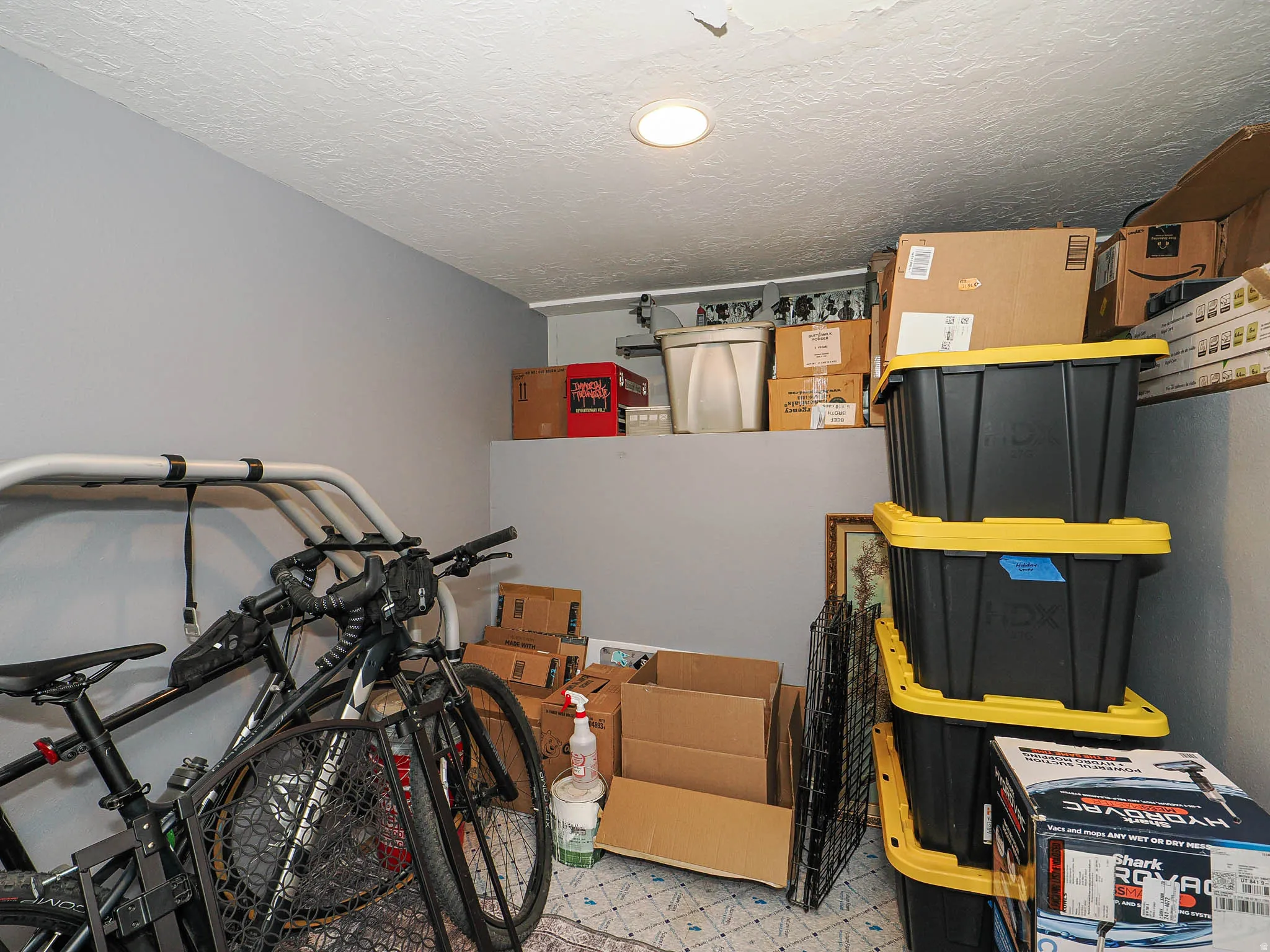 Recessed ceiling light illuminating a storage area with a built-in elevated shelf and light gray painted walls