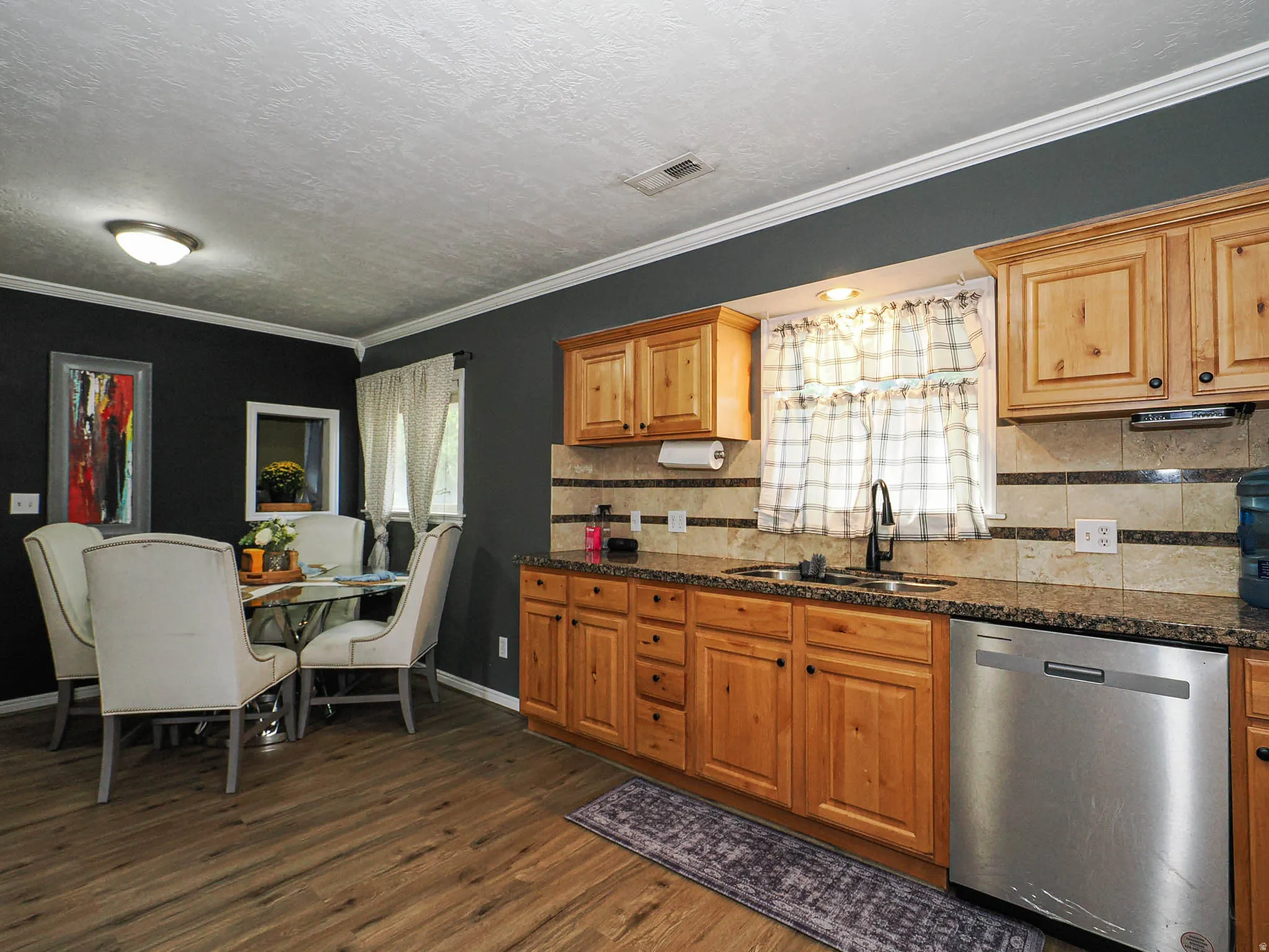 Kitchen with wood-finish flooring, natural wood cabinetry, and a stone-look backsplash