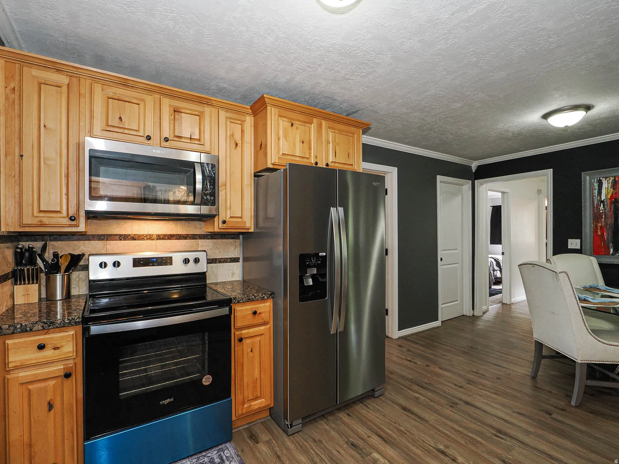 Kitchen featuring wood cabinetry, stainless steel appliances, dark stone countertops, and a tile backsplash
