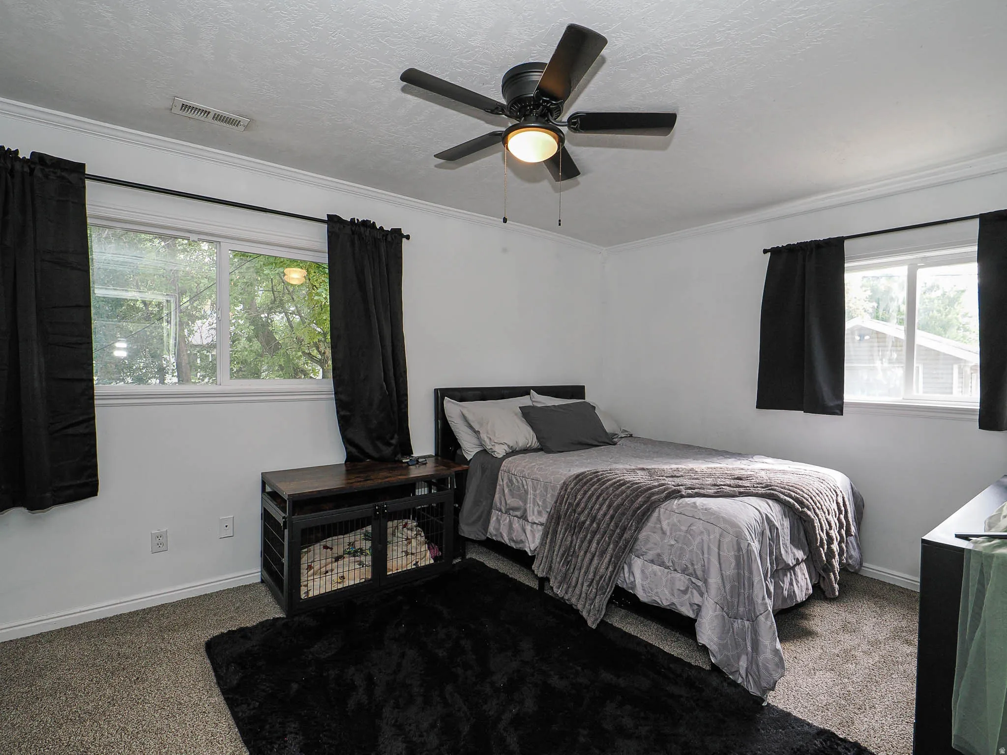 Bedroom featuring two windows with white trim, gray carpet, and a ceiling fan with integrated lighting