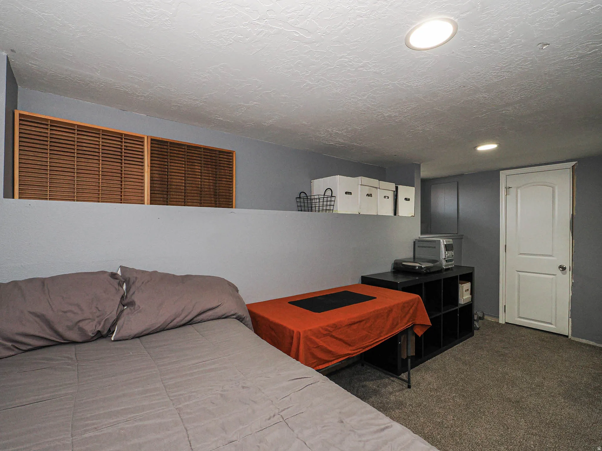 Carpeted room featuring a half-wall with wood louvered accents, recessed lighting, and a white interior door