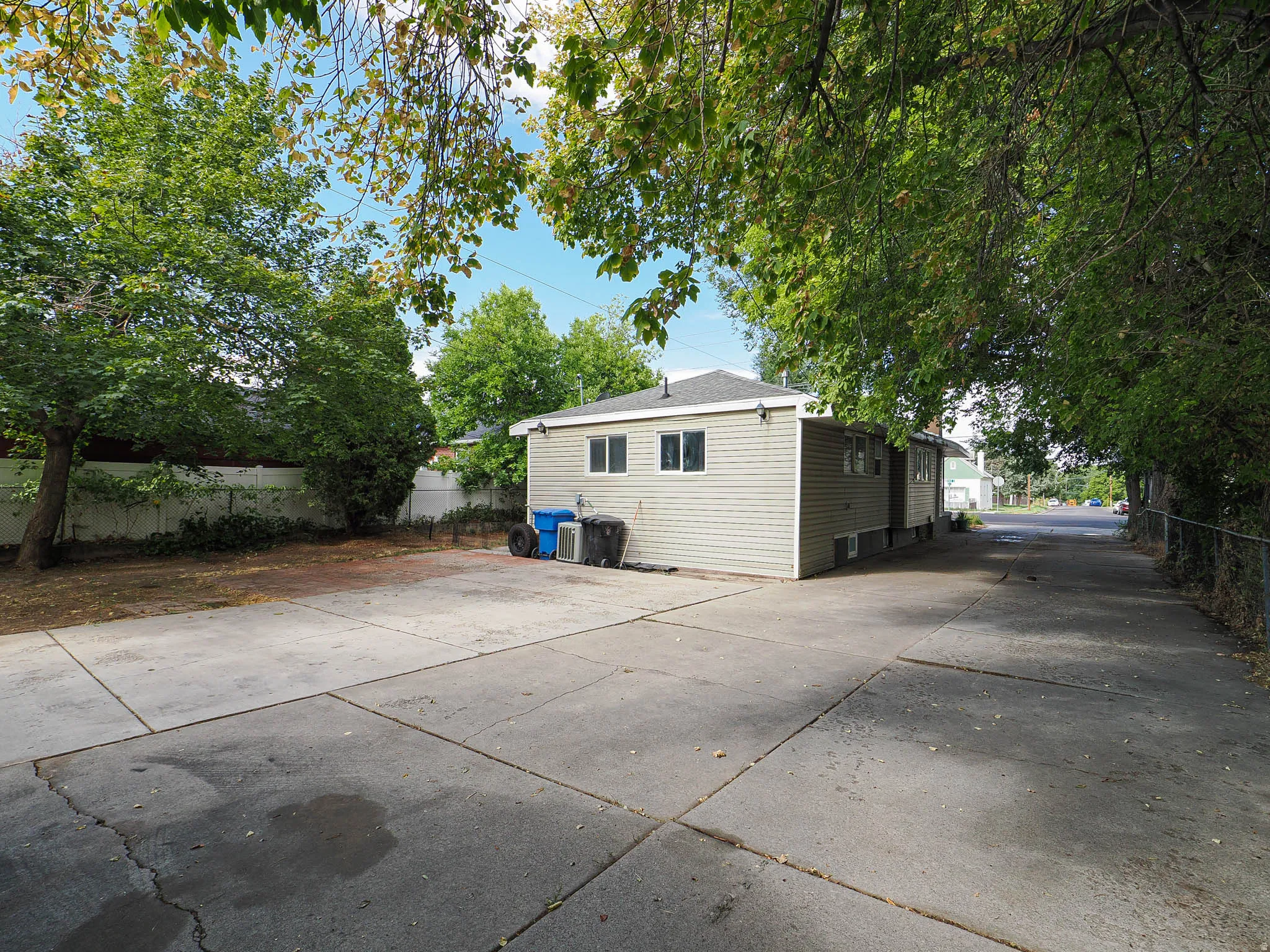 Expansive concrete driveway beside a light-colored siding structure with multiple windows
