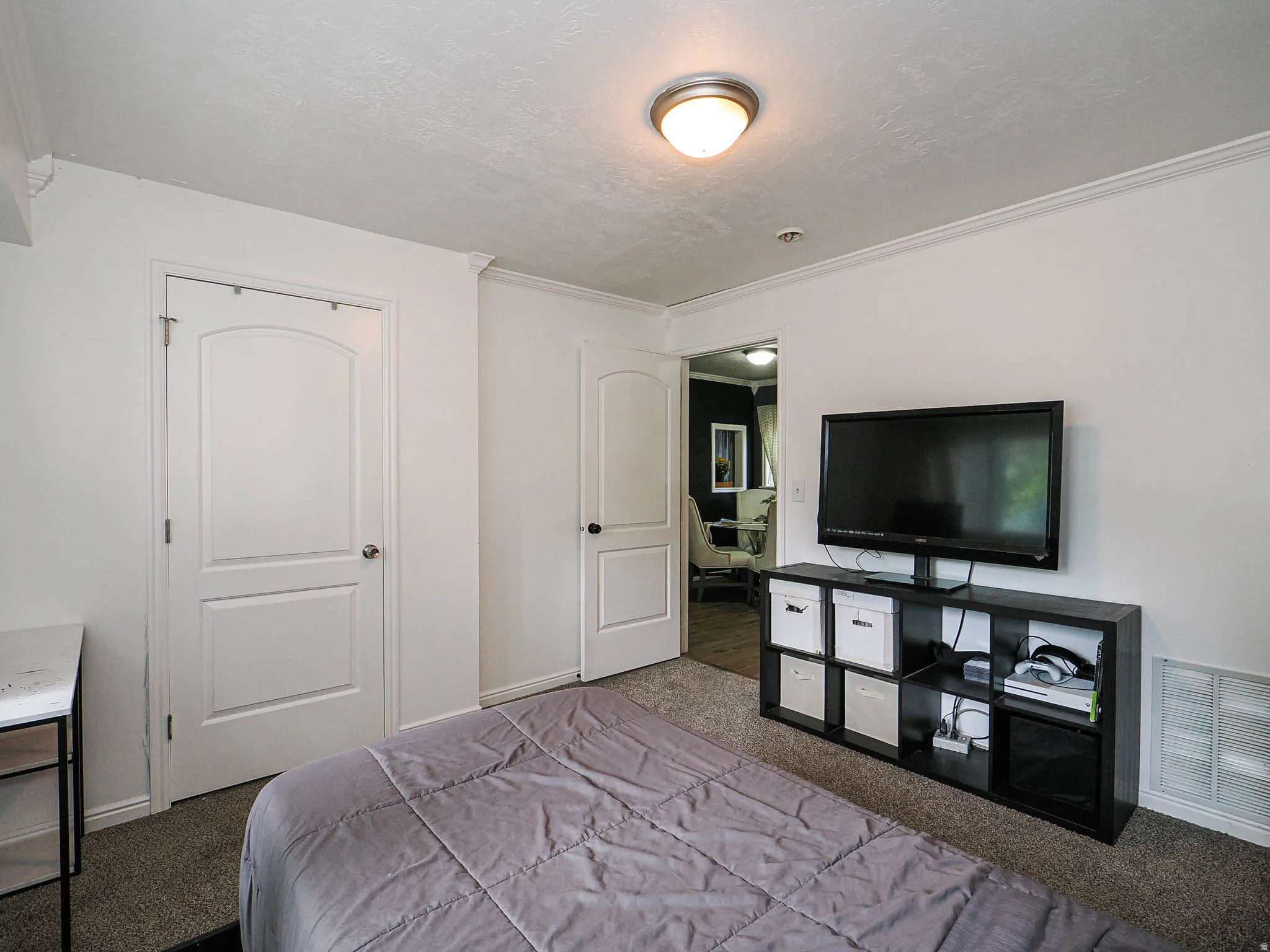 Bedroom featuring two paneled doors, crown molding, wall-to-wall carpeting, and a semi-flush mount ceiling light fixture