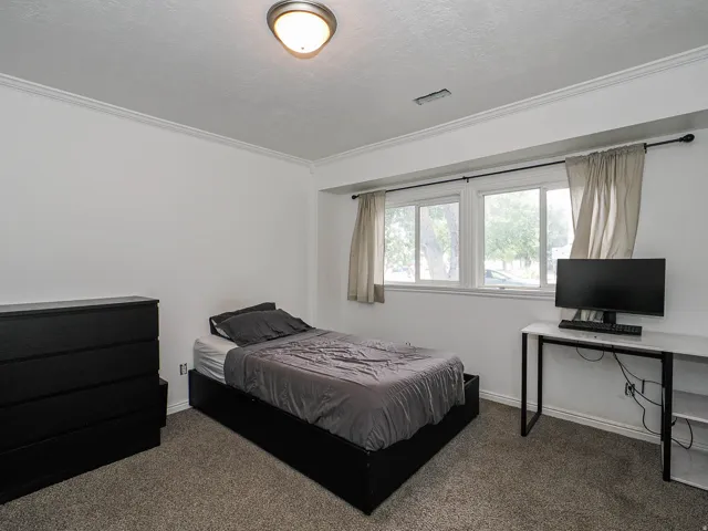 Room featuring white walls, crown molding, and a dual-pane window with white trim