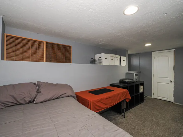 Carpeted room featuring a half-wall with wood louvered accents, recessed lighting, and a white interior door