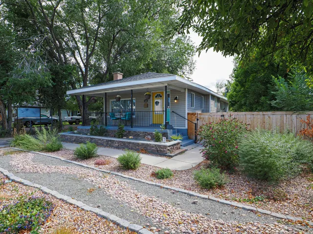 Charming single-story residence featuring a covered front porch, a bright yellow entry door, and light gray siding