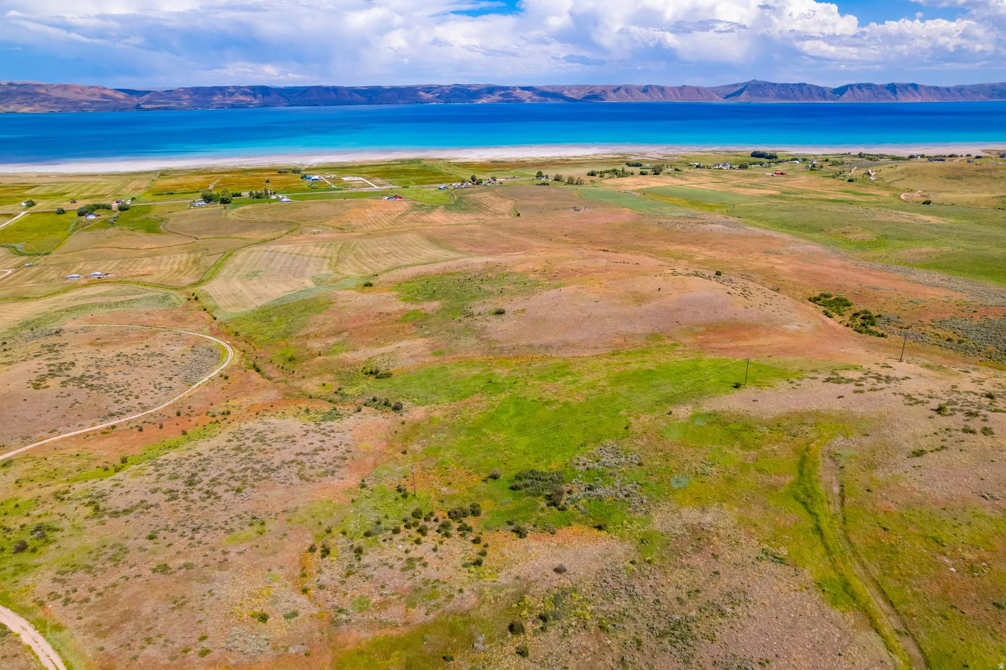 Expansive rural landscape featuring a prominent body of water, distant mountains, and varied terrain