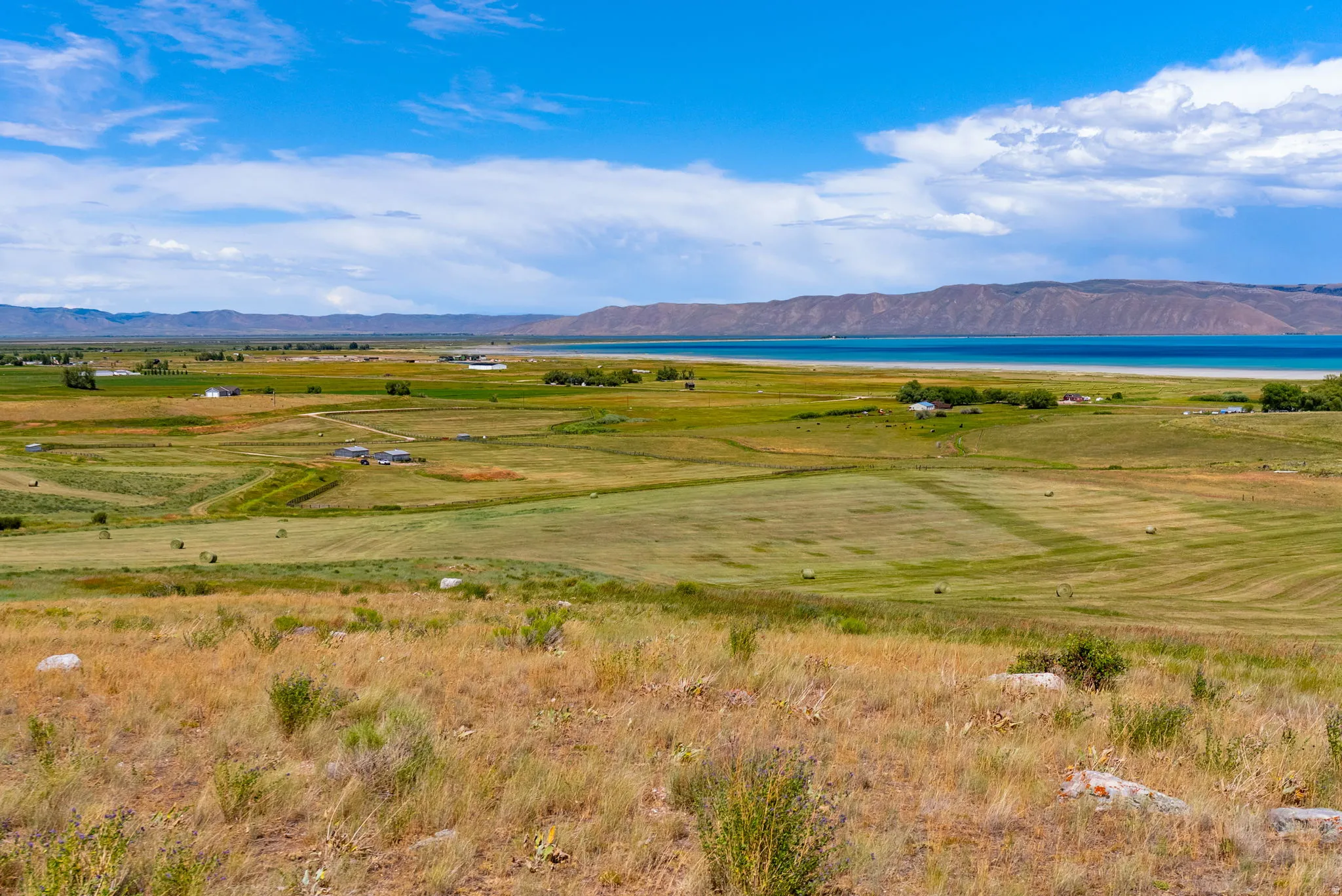 Expansive rural landscape featuring a freshwater lake with distant mountains