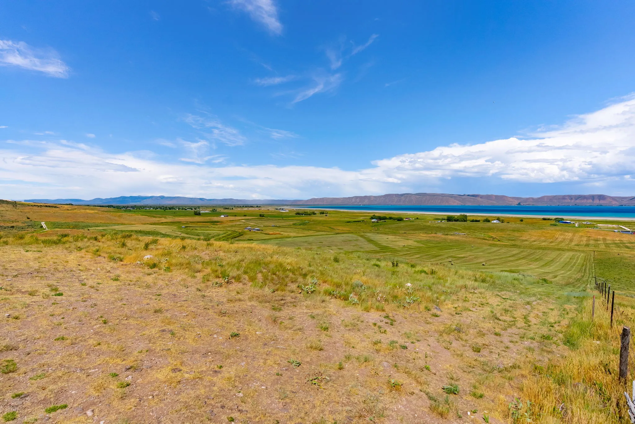 Expansive, open land featuring varied topography, distant water, and mountain scenery