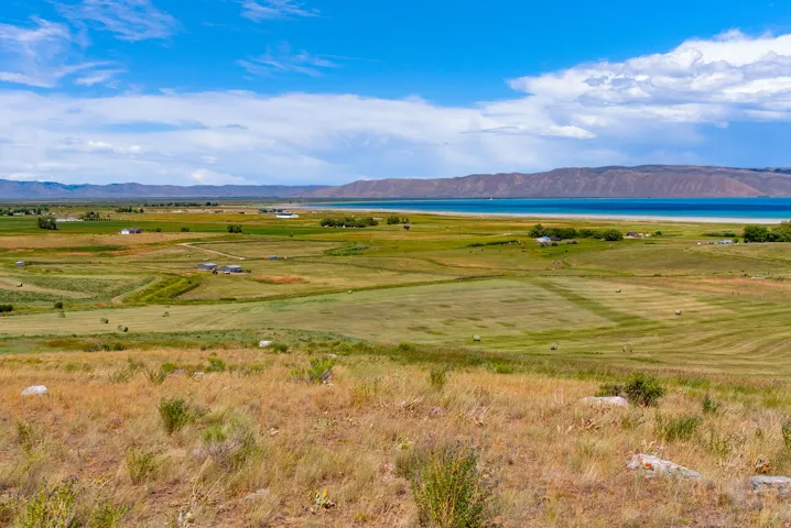Expansive rural landscape featuring a freshwater lake with distant mountains