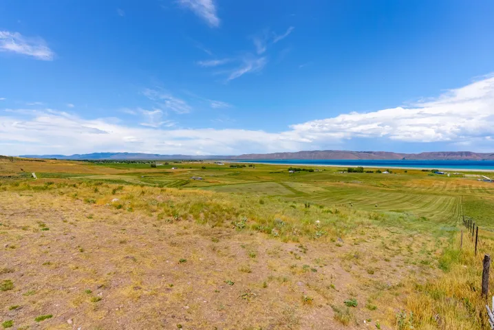 Expansive, open land featuring varied topography, distant water, and mountain scenery