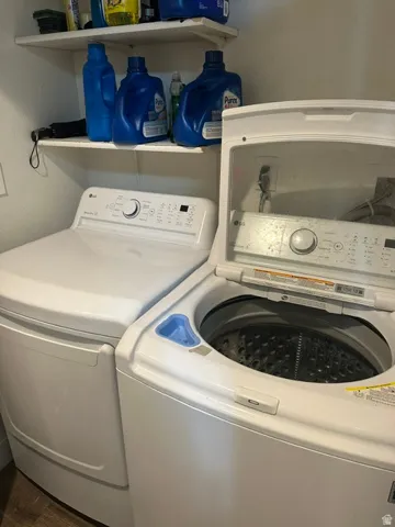 Dedicated laundry area featuring a top-loading washing machine and a front-loading dryer, complemented by two wall-mounted storage shelves