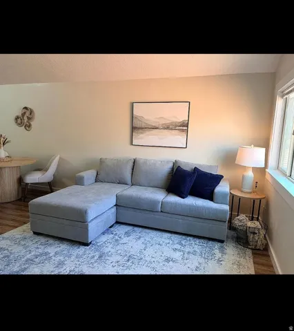 Open-concept living space featuring wood-finish flooring, light-toned walls, and a large window providing natural illumination