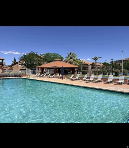 Resort-style aquatic area featuring a large swimming pool with concrete decking, a central shaded gazebo, and surrounding lounge seating