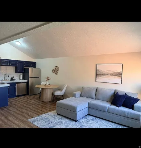 Vaulted ceilings accent an open-concept living area with wood-finish flooring
