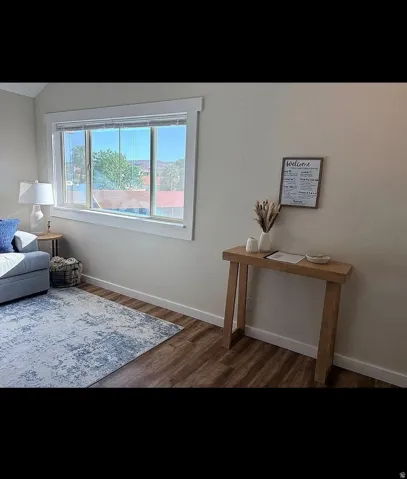 Bright interior space featuring a large window with white trim, wood-finish flooring, and light-toned walls
