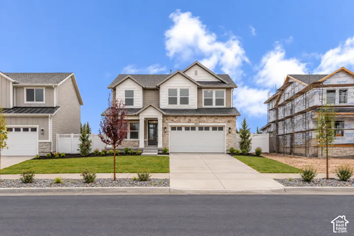 Two-story exterior featuring multi-textured siding, stone veneer accents, a covered front entryway, and a three-car garage