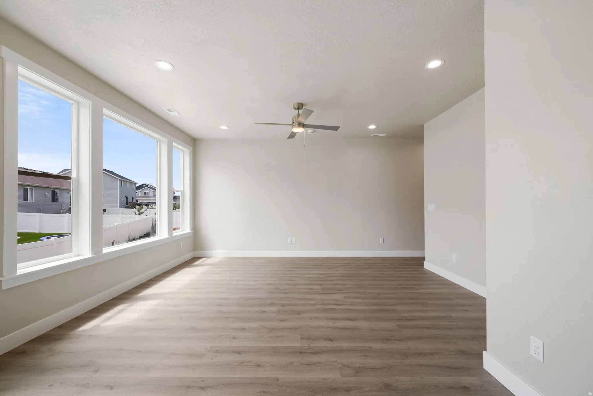 Spacious interior featuring wood-finish flooring, a contemporary ceiling fan, and recessed lighting