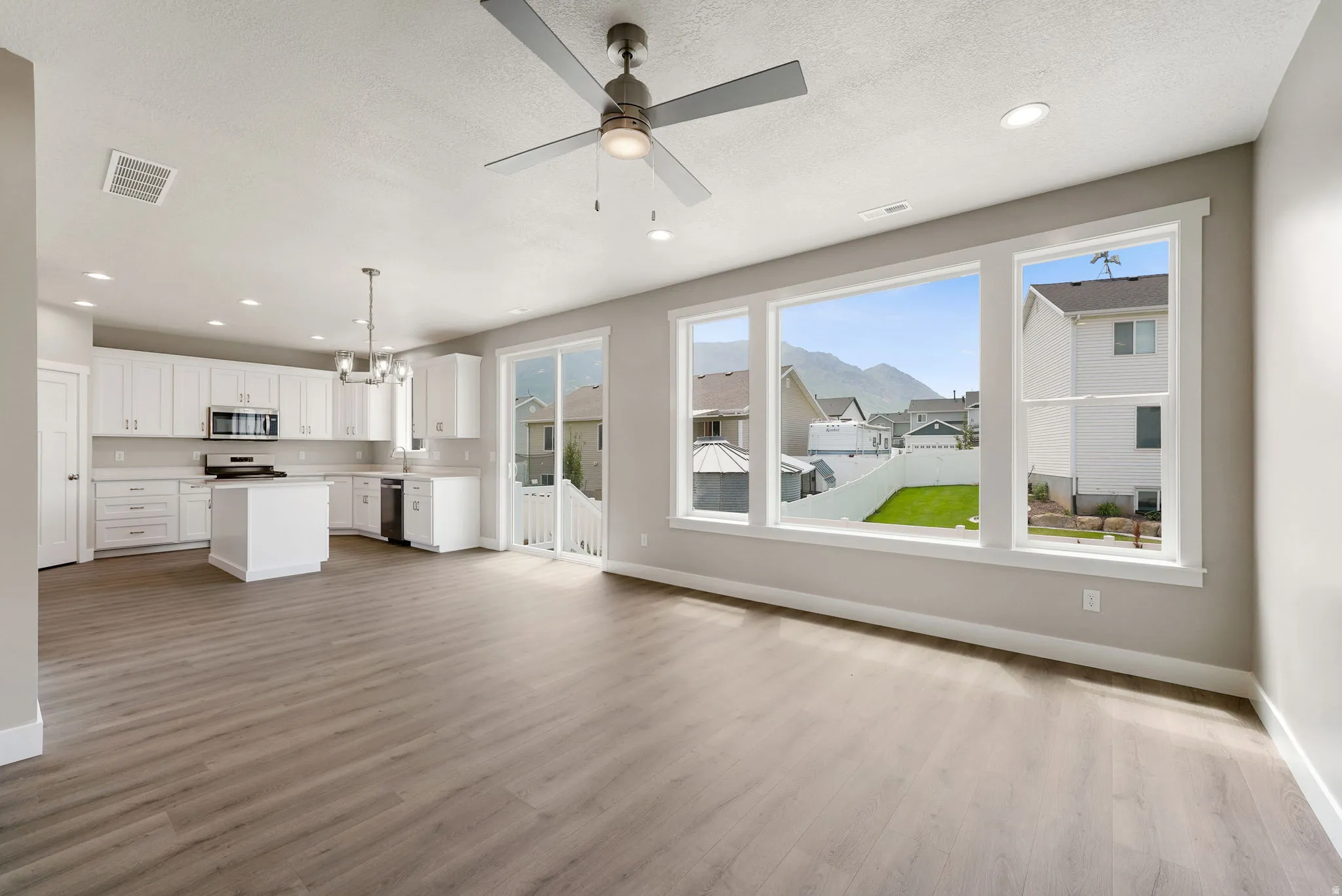 Open-concept living space featuring wood-finish flooring, a modern ceiling fan, and recessed lighting
