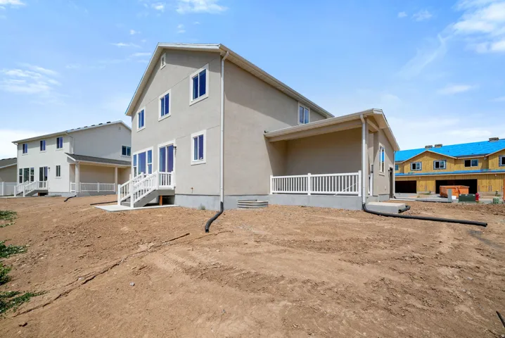 Rear exterior featuring a covered patio with white railing, a walk-out basement entry with a concrete patio, and a second-story balcony
