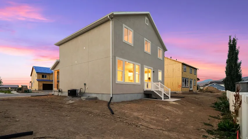 Contemporary stucco exterior with multiple windows, a white railing staircase, and a concrete patio