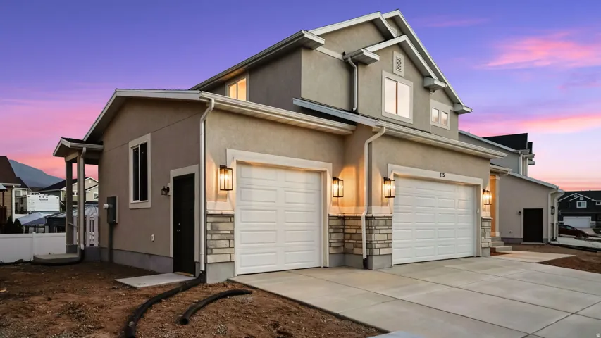 Two-story stucco exterior featuring stone accents, two-car garage, and multiple windows
