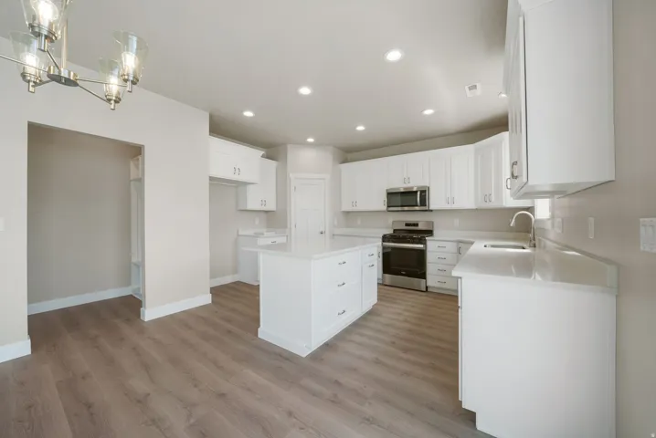 Modern kitchen featuring white cabinetry, a center island with countertop, stainless steel appliances, recessed lighting, and wood-finish flooring