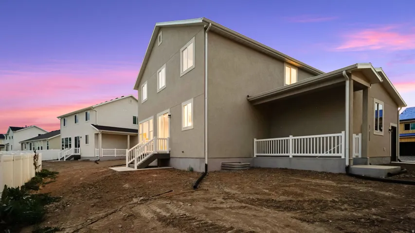 Rear exterior featuring a covered patio, white railing, and a private back entrance with stairs