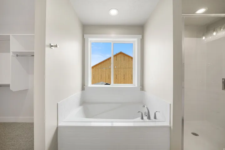 Soaking tub with white subway tile surround, polished chrome fixtures, and a clear glass shower enclosure