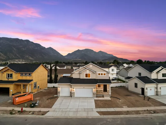 Contemporary two-story residence featuring a neutral stucco and stone facade, dual garage doors, and a covered entry