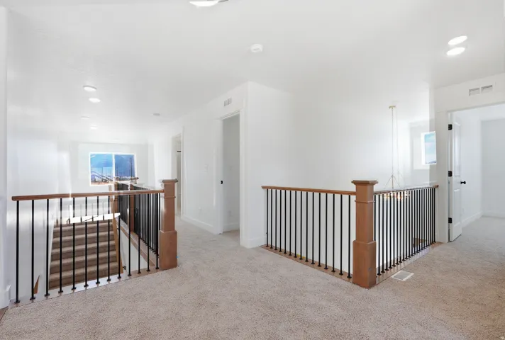Upper-level landing featuring light brown carpeting and white walls