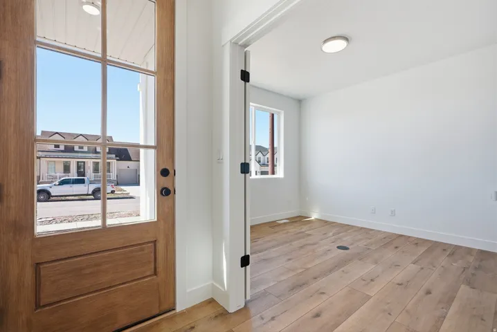 Entryway featuring a wood-panel door with glass lites, a flush-mount ceiling light, and wood-finish flooring extending into an adjacent room