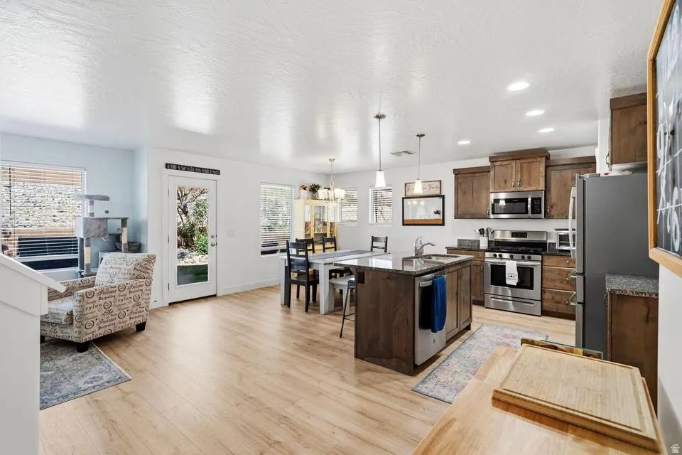 Open-concept kitchen and dining area featuring wood-finish flooring, recessed lighting, and stainless steel appliances