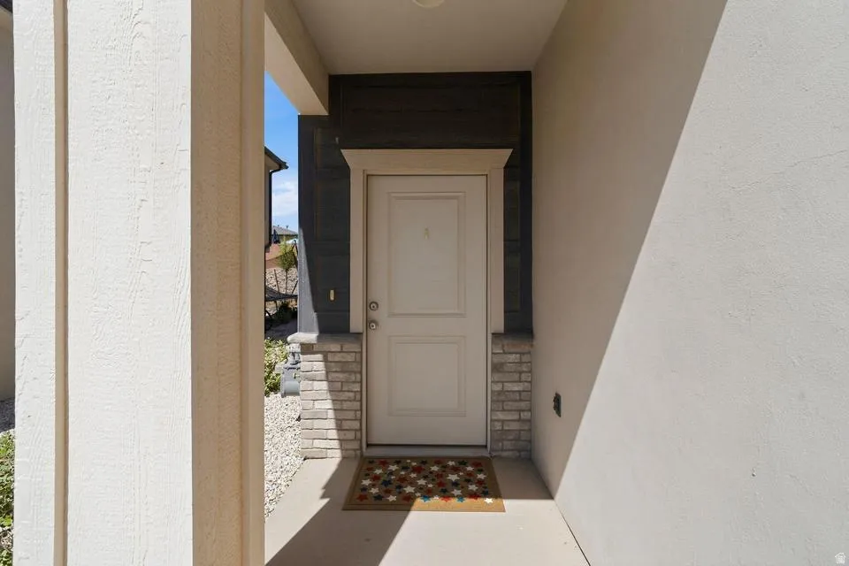 Covered entry featuring a paneled door, stone facade accents, dark horizontal siding, and textured exterior walls