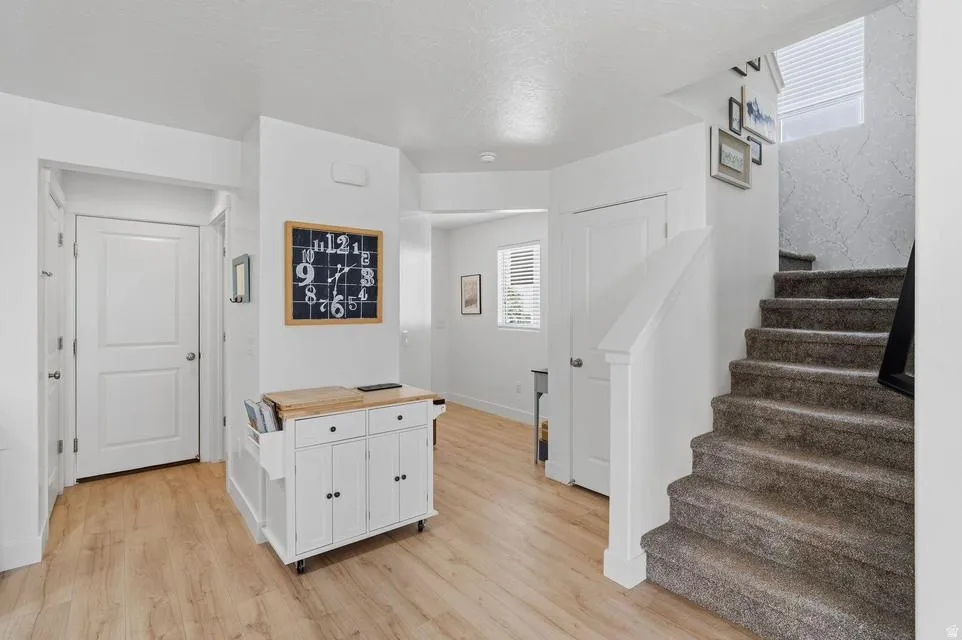 Entryway featuring wood-finish flooring, white paneled doors, and a carpeted staircase