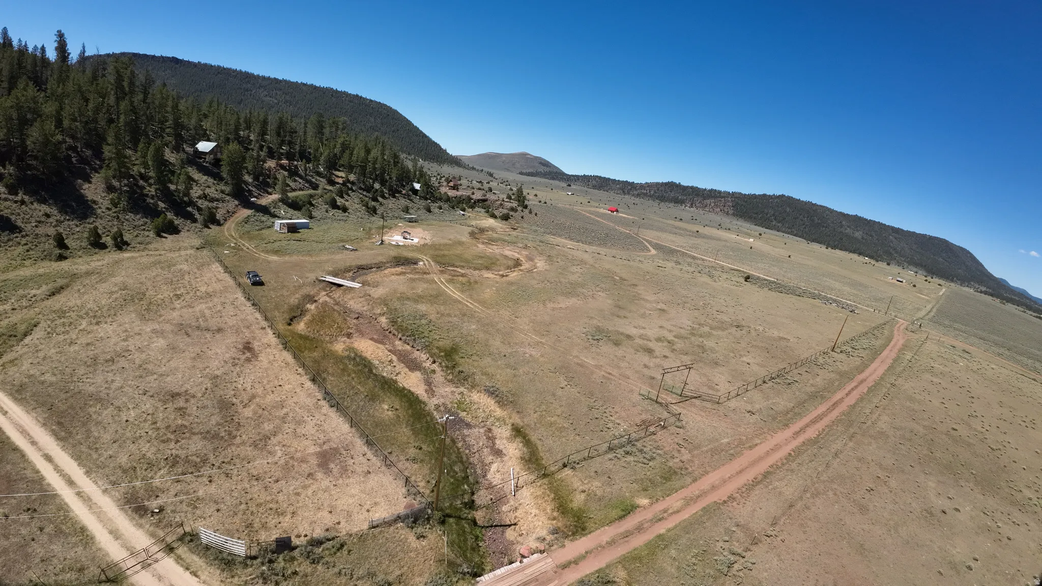Expansive acreage featuring a dirt road, multiple outbuildings, and natural terrain